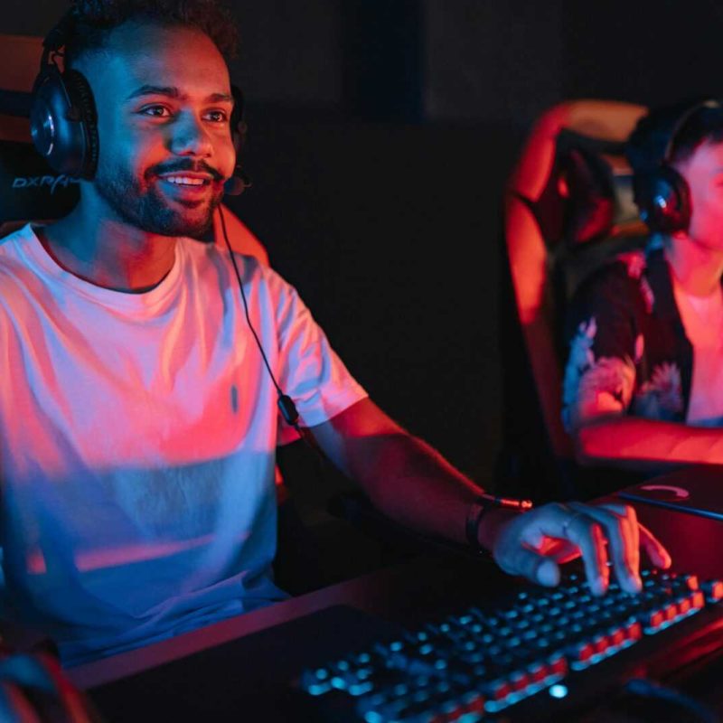 pexels-photo-9072342-9072342-1 Two male gamers intensely focused during a gaming session in a cybercafe with colorful lighting.
